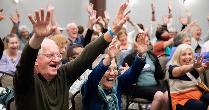 Participants raise their hands at the caregivers event.