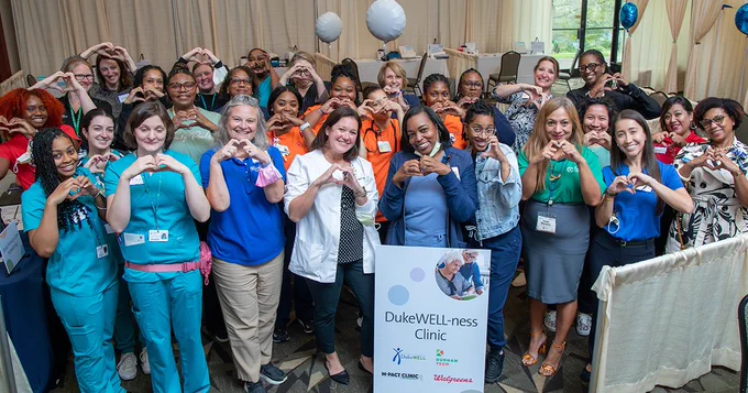 Members of DukeWell-ness clinic hold their hands up as hearts at the caregivers event.