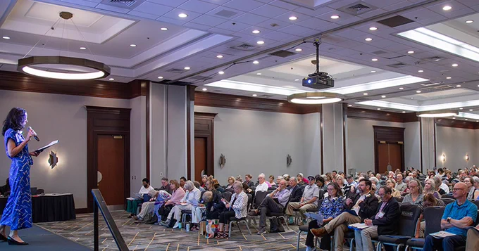 Speaker presents to a large group in a conference room at the caregivers event.