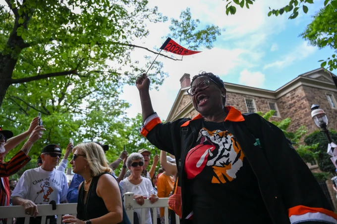 An alumna with a tiger shirt waves a 2028 flag