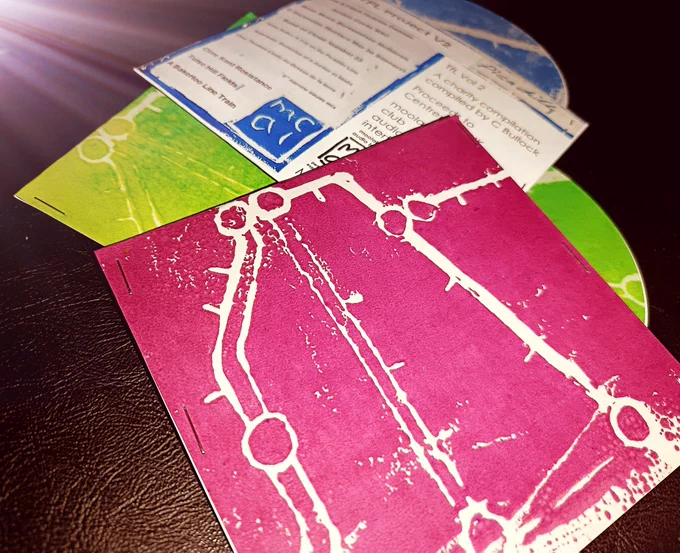 Three CDs showing the hand crafted card sleeves and 3 colour options: maroon, green and blue 