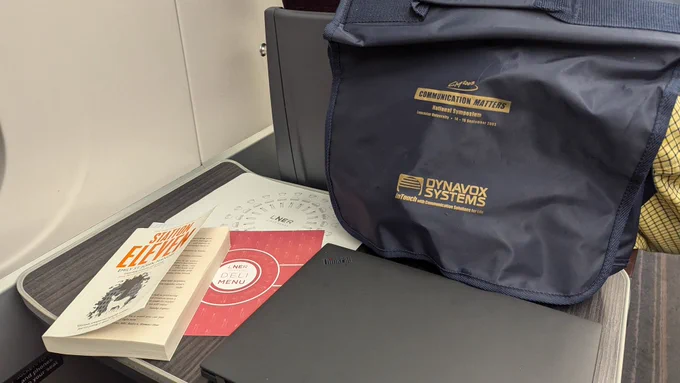 A train table with a book, laptop and a bag. 