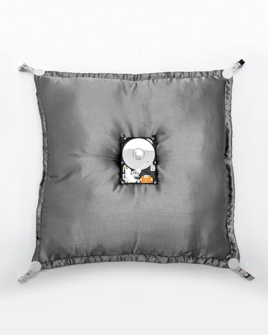 An exposed computer hard drive (HDD Toshiba MK2109MAT 2GB 5.4K IDE 2.5") rests on a silver satin royal pillow. The pillow has four tassels on the corners made from computer cables and connectors.