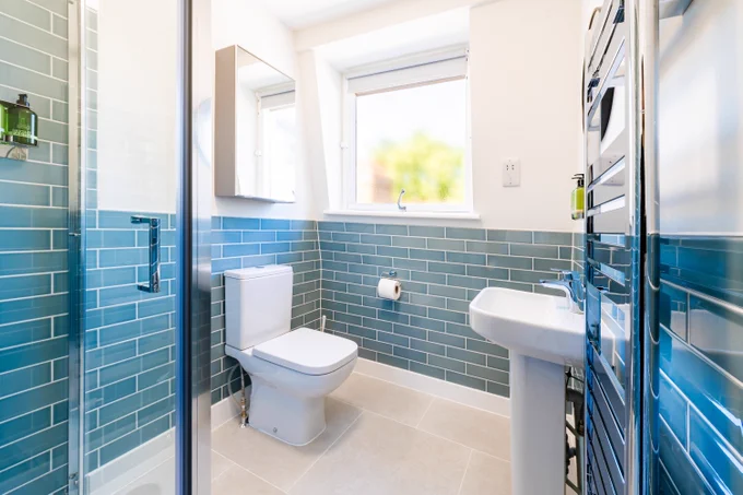 White bathroom with white sanitary wear and teal bathroom tiles