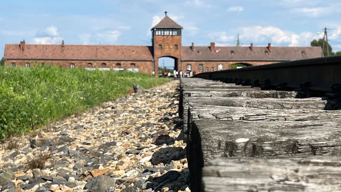The gate of the former Auschwitz II-Birkenau camp. Structures of the rail link in the foreground.