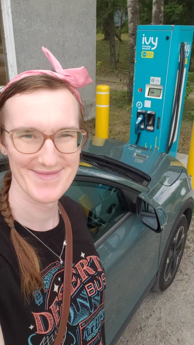 Photo of me standing in front of my green vehicle and blue Ivy charging station