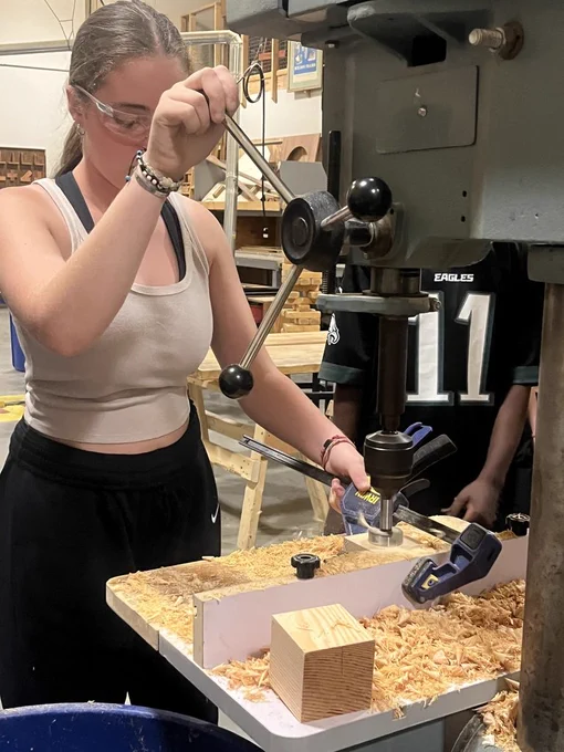 Student cutting piece of wood in carpentry
