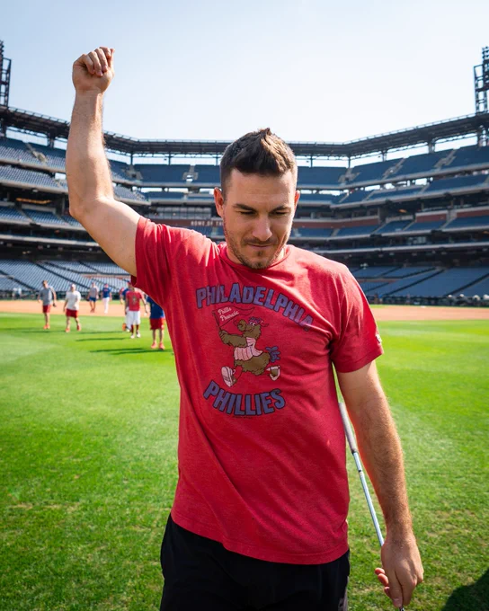 J.T. Realmuto holds his hand in the air. He is wearing a red t-shirt with the Phanatic on it