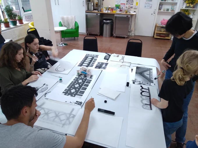 photo of a workshop - people sitting round a large white table drawing