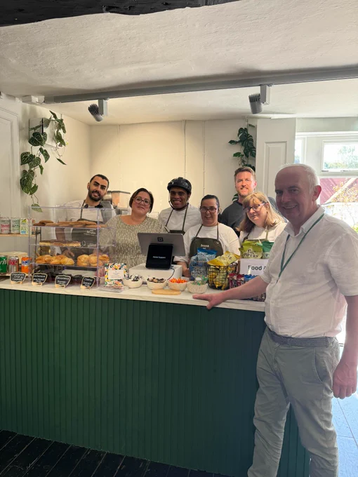 The photograph is of the Leader of Sutton Council, Councillor Barry Lewis, with six members of Nickel Support team. They are standing at the cafe's serving counter.