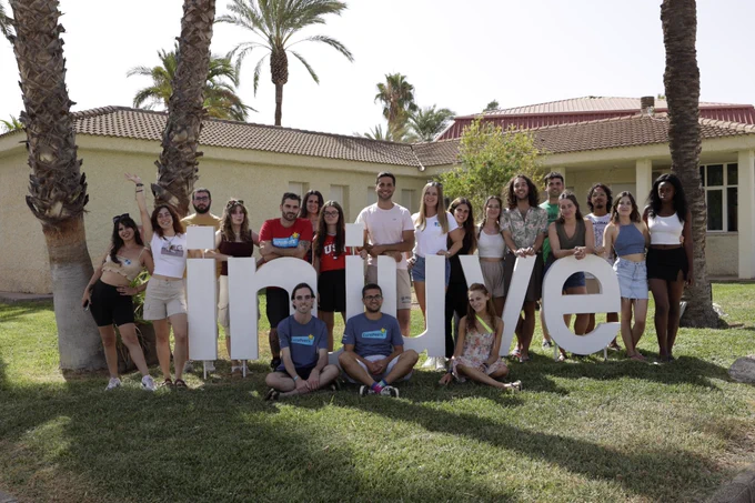 Imagen fotográfica de los y las participantes en el 'I Encuentro Anual de EuroPeers', en el CEULAJ (Mollina, Málaga), junto a cartel que conforman las letras del Injuve. 
