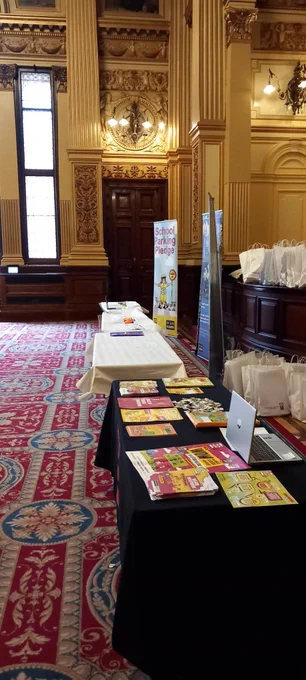 Two tables  filled with colourful information leaflets about WOW - the walk to school challenge in a gilded room in the Glasgow City Chambers.