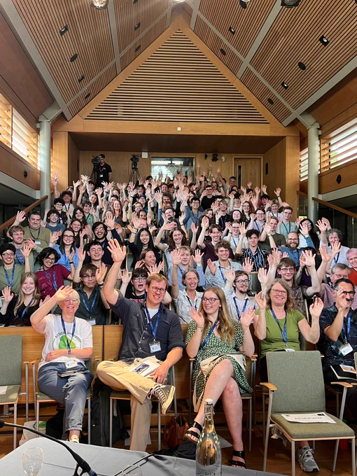 BUC attendees in the auditorium at Queen's College, Oxford, waving at the camera