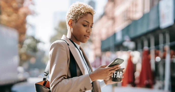 A person holding a coffee and a cell phone.