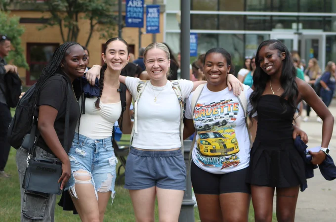 Five students pose for a photo outside