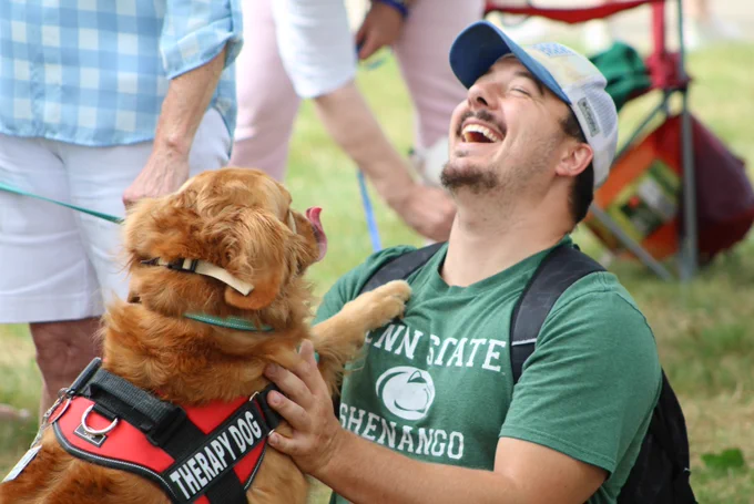 Student laughs while petting a dog