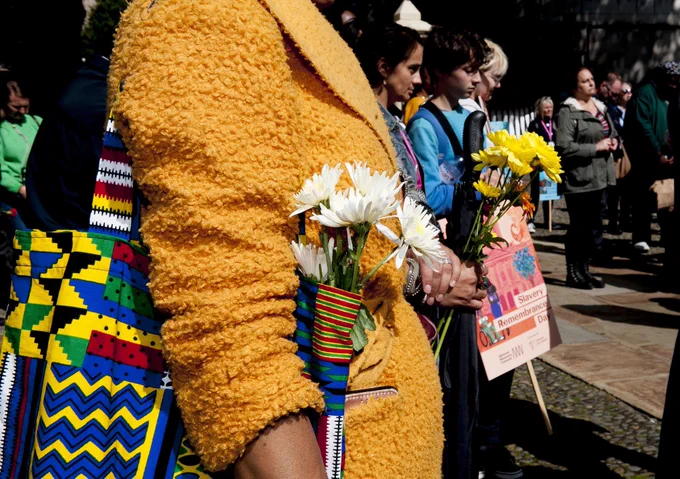 Figure in yellow jacket holding white flowers