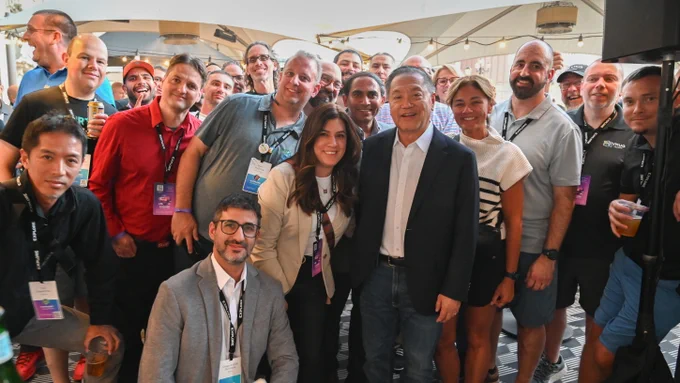 Group of VMware User Group members and Hock Tan, President and CEO of Broadcom, smiling at a social event.