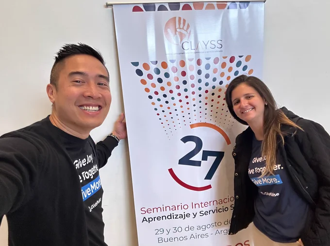 Una foto de George y Alicia en CLASS frente al cartel de bienvenida de la conferencia.
