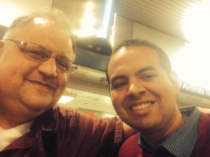 Steve Silberman, an older white man with glasses, smiling with Eric, a younger Latino man.