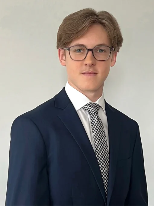 Mark Seemann | Mechanical Engineering Student wearing a blue suit with a checkered tie and looking confidently at the camera.