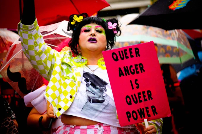Emma Panda poses with a sign that reads "Queer Anger Is Queer Power" during the parade at Dover Pride 2024.
