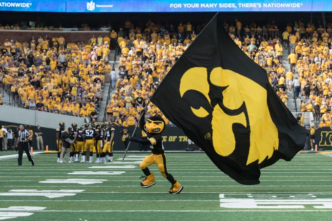 Herky runs with hawkeye flag