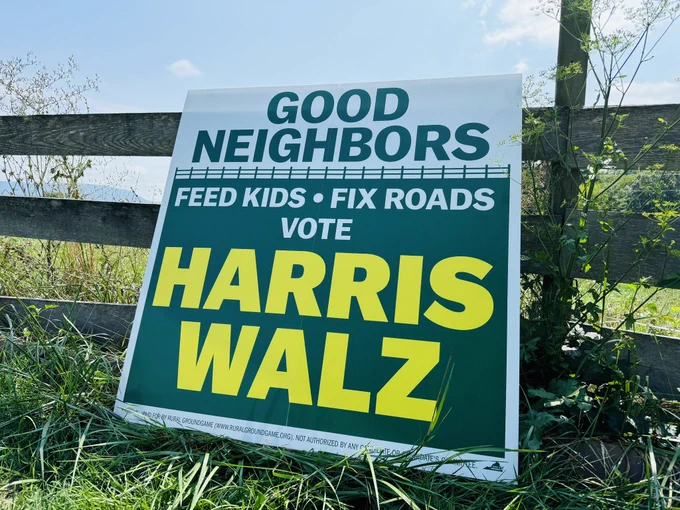 Large barn sign on a fence. “good neighbors feed kids, fix roads, vote Harris Walz”