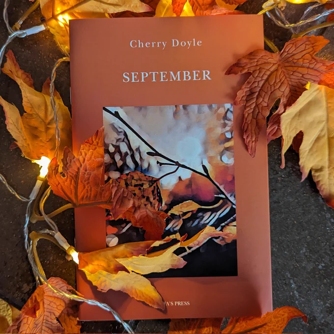 September surrounded by a fairy lights and autumn leaves garland. 