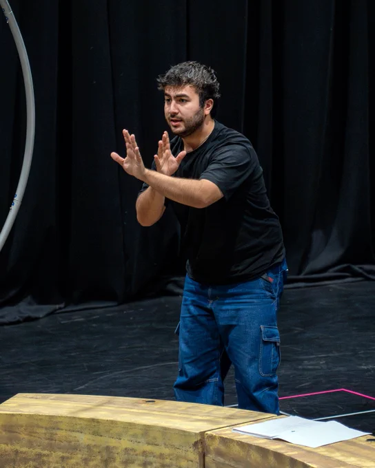 A man on stage signalling not to be afraid 