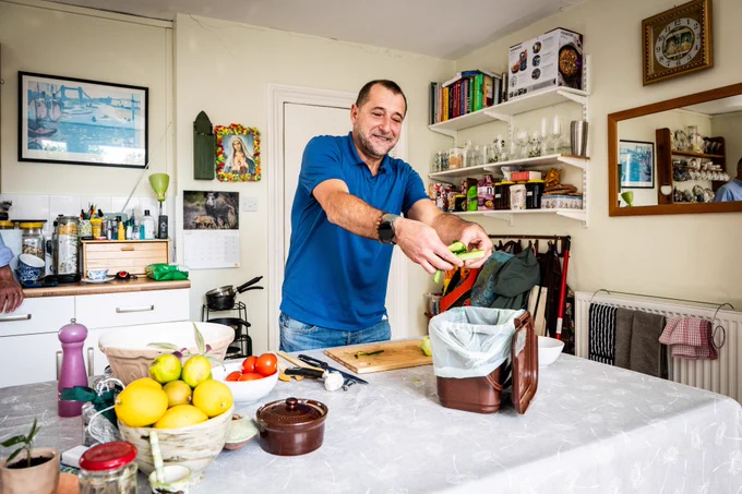 A photograph of a person recycling their food waste while cooking a meal