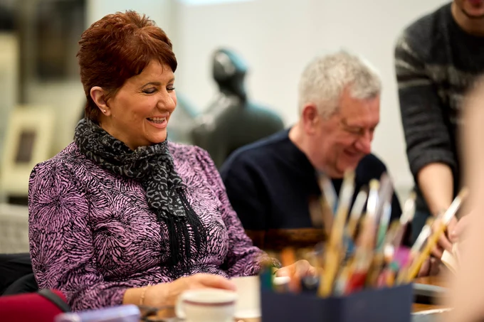 Two people laughing whilst doing craft activities.