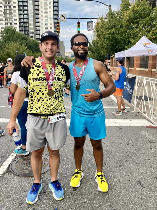 Tevin and his guide pose after the finish with their medals