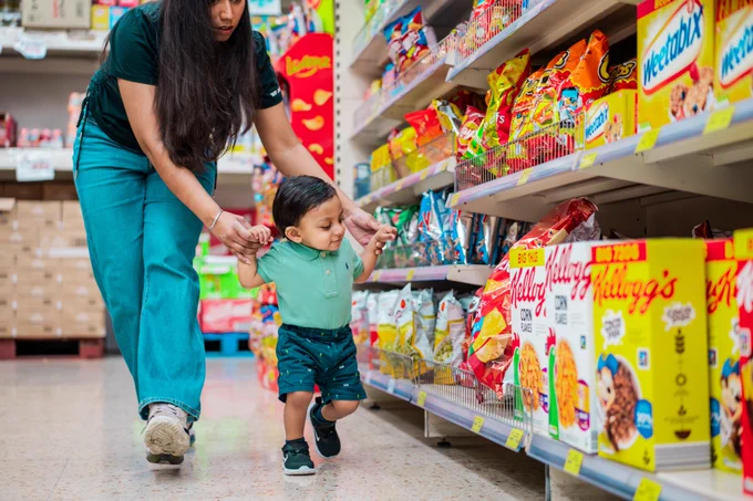 A small child looks at a brightly coloured cereal box placed at eye level. 

Image: © 2023. Provided by Impact on Urban Health licensed via a CC BY-NC-ND 4.0 license