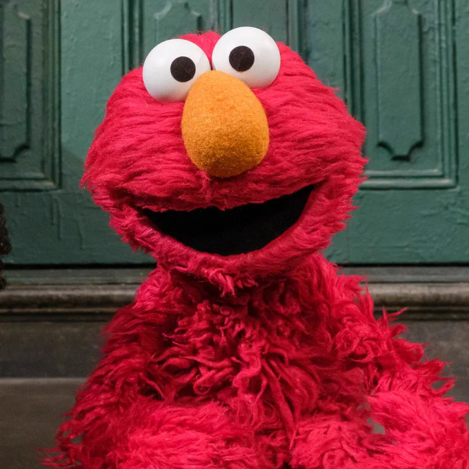 Elmo smiling and sitting on the 123 Sesame Street stoop