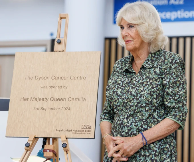 Her Majesty The Queen stands next to a plaque marking the opening of the Dyson Cancer Centre.