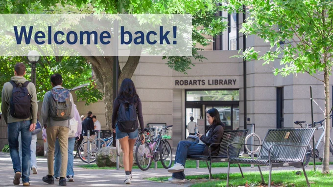 image of a student walking in front of Robarts Library. a student is seated on a bench with bicycles in the background.   