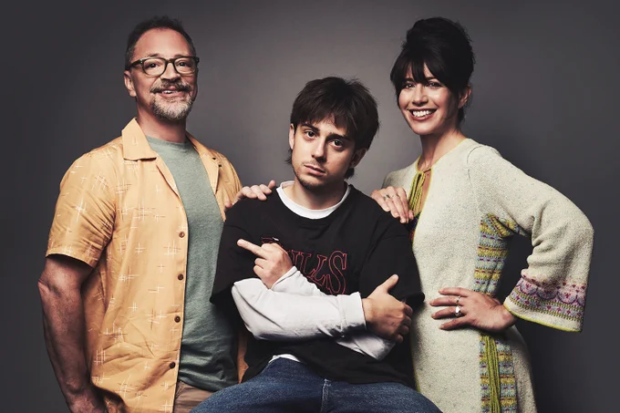 A photo showing three individuals on a darkened grey background