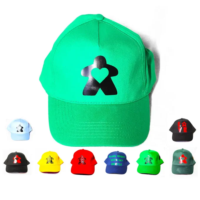 Baseball caps in a variety of colours with board game related designs: text saying "game night with my meeple", Atikin Games text with cat logo, "love" with the O as a meeple, a meeple with a heart cutout and a meeple with star design

