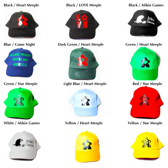 Baseball caps in a variety of colours with board game related designs: text saying "game night with my meeple", Atikin Games text with cat logo, "love" with the O as a meeple, a meeple with a heart cutout and a meeple with star design