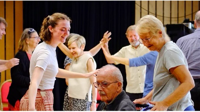A group of adults smiling and dancing at the Cambridge Junction.