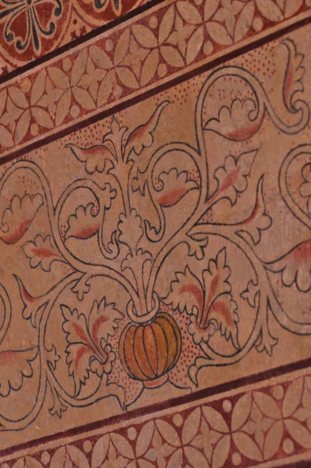 Wallpainting at St. Peter's Northampton, showing floral patterns coming out of a pumpkin-like vase surrounded by floral red borders.