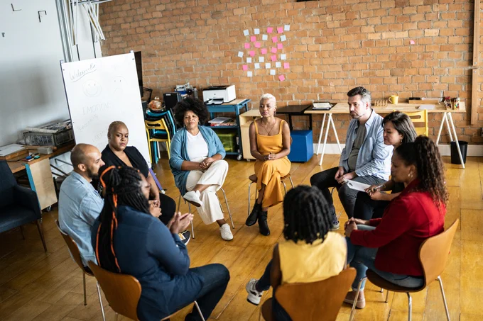 A diverse group of people sitting in a circle during a meeting