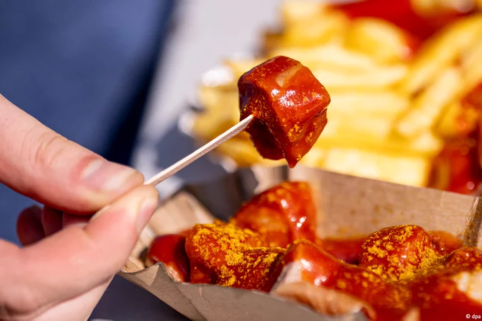 Sliced Currywurst in a paper tray with fries.