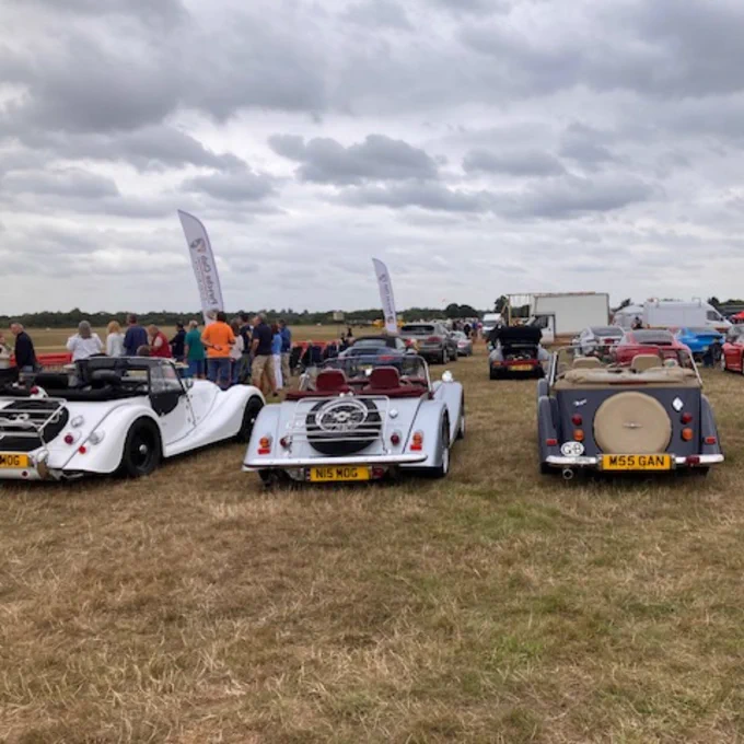 Image of dozens of vintage cars parked in a field.