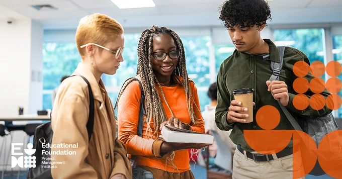 Three young adults standing in a library looking at a book together