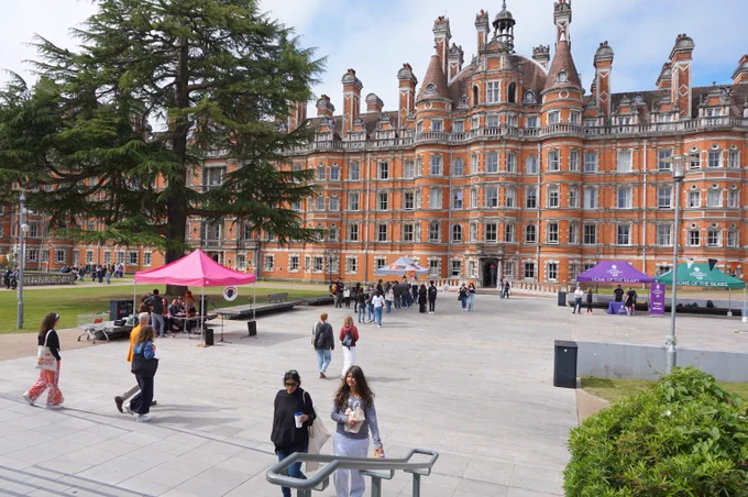 Visitors walking and gathering near tents in Founder's square. The Founder's Building is featured in the background. 