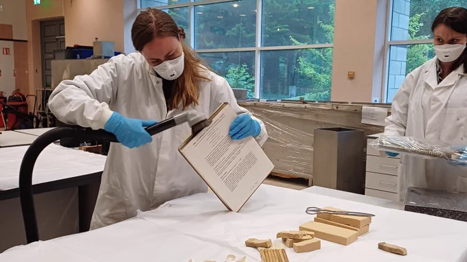 Cleaning the top edge of a book with an HEPA vacuum cleaner, with smoke sponges and brushes prepared for further cleaning (image by Connie Bettison © National Museum of Ireland)
