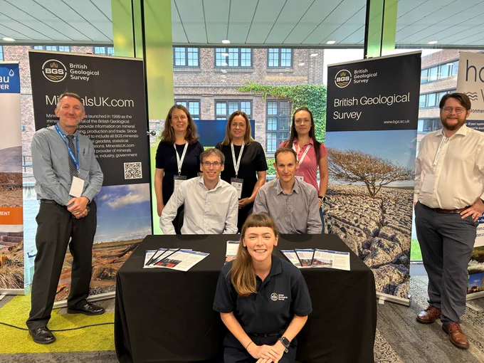 Members of BGS staff at the EIG conference. They are stood in front of a table with two BGS-branded pop-up banners either side of them.