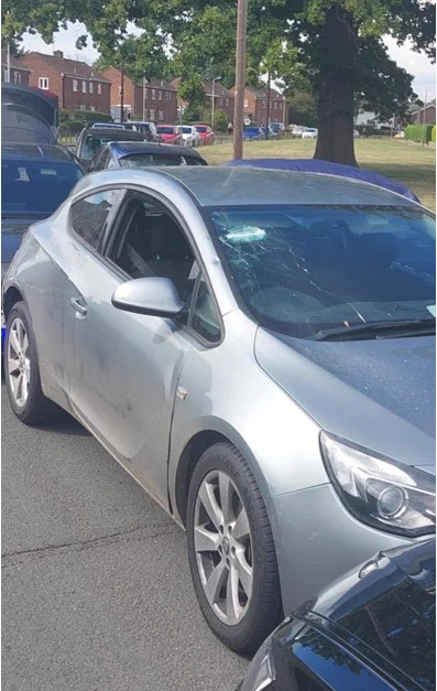 Image of a silver car with a smashed upper left windscreen